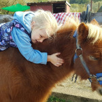kleines Mädchen kuschelt mit Pferd